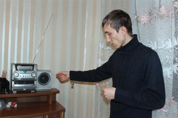 Виталий вешает колокольчики, которые будут громко звучать, если кто-то дернет за них или за нитку, на которой они подвешены